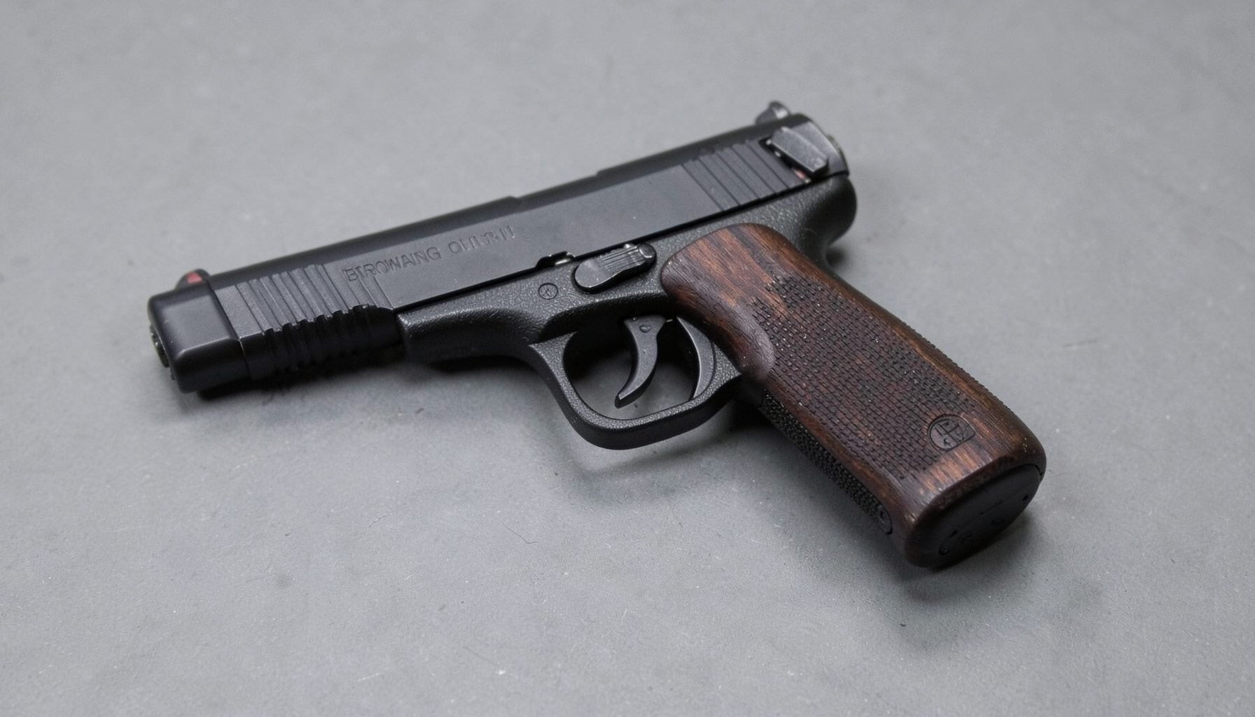 A compact Browning Challenger II 22 LR pistol with dark finish and slim wood grips, resting on a muted gray surface