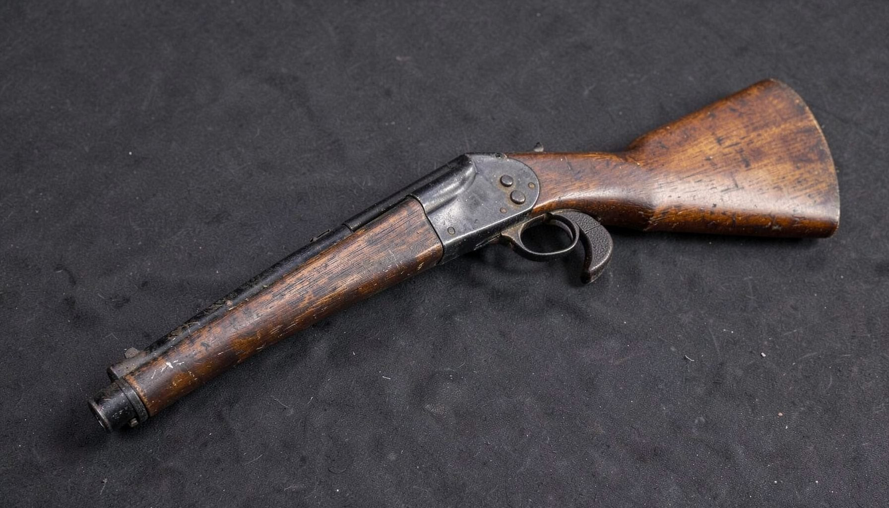 A vintage Browning FN-made Auto-5 12 gauge shotgun with distinctive humpback receiver and aged walnut stock, photographed on a dark textured surface